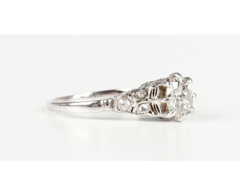 A diamond ring, claw set with the principal circular cut diamond in a raised design between rose cut diamond set three stone 