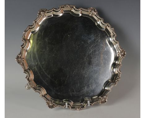 A George V silver salver, the piecrust border with cast egg and dart and scallop rim, raised on four volute scroll feet, Shef