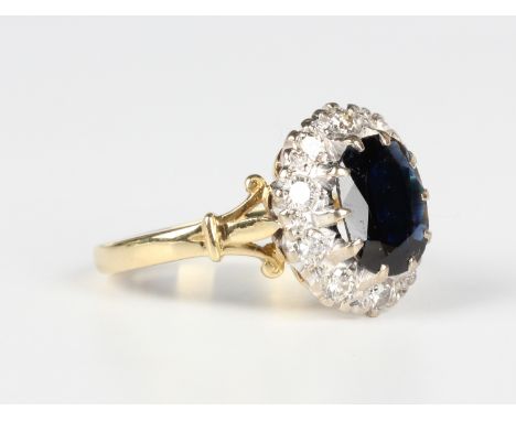 An 18ct gold, sapphire and diamond oval cluster ring, claw set with the oval cut sapphire within a surround of circular cut d