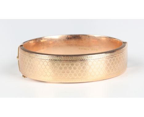 A 9ct gold oval hinged bangle with engine turned decoration, Birmingham 1935, weight 31.5g, inside width 5.8cm.Buyer’s Premiu