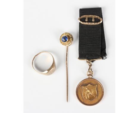 A gold and sapphire stickpin, the finial of circular form, collet set with a circular cut sapphire within a border engraved '