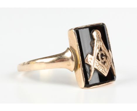 A gold and black onyx Masonic ring, the curved rectangular black onyx panel applied with a square, compasses and initial 'G' 