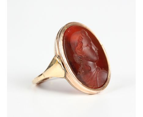 A gold and oval cornelian signet style ring, mounted with a cornelian intaglio designed as a portrait of a classical lady, de