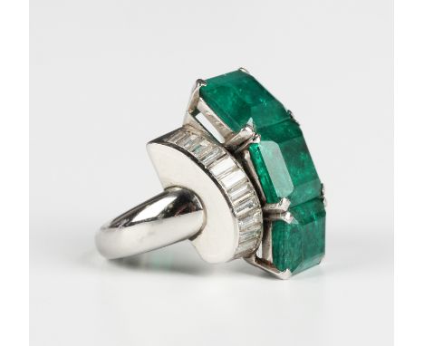 A platinum, emerald and diamond ring, 1950s, claw set with a graduated row of three large cut cornered rectangular step cut e