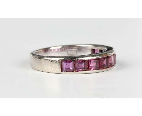 A white gold and ruby half eternity ring, mounted with a row of square cut rubies, detailed '585', weight 4.1g, ring size app