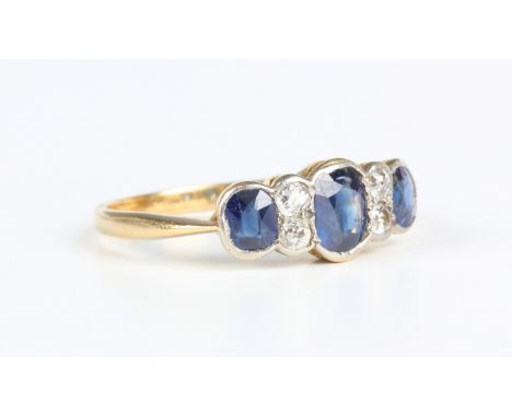 A gold, sapphire and diamond ring, mounted with three oval cut sapphires alternating with two pairs of cushion cut diamonds, 