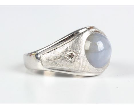 A 9ct white gold, cabochon star sapphire and diamond three stone ring, mounted with the circular cabochon star sapphire betwe