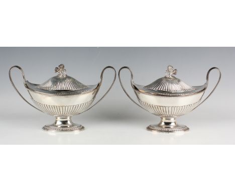 A pair of George III silver sauce tureens, covers and liners, each of half-reeded boat-shaped form, flanked by a pair of reed