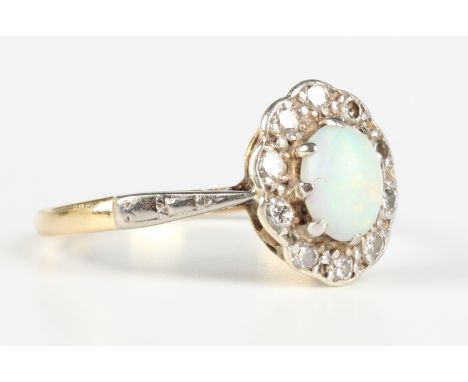 A gold and platinum ring, claw set with an oval cut opal within a surround of circular cut diamonds, indistinct mark, weight 