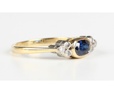 An 18ct gold ring, collet set with an oval cut sapphire between circular cut diamond set three stone shoulders, London 1994, 