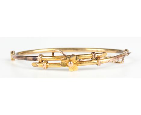 An Edwardian gold oval hinged bangle, the front with a trefoil shaped motif, otherwise in a twist design, on a snap clasp, in