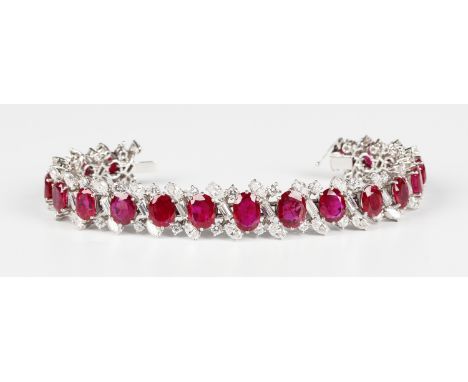 A platinum, ruby and diamond bracelet, the centre claw set with a row of nineteen graduated oval cut rubies, otherwise claw s