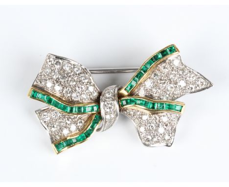 A diamond and emerald brooch in the form of a ribbon tied bow, mounted with square cut emeralds and circular cut diamonds, un