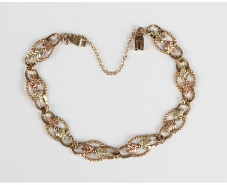 A two colour gold bracelet, the openwork shaped oval links with leaf motifs, detailed '10K', on a sliding clasp, detailed '14