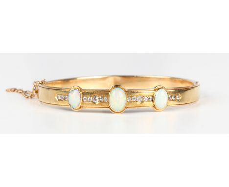 A gold, opal and diamond oval hinged bangle, circa 1900, collet set with three oval opals spaced within a row of old mine cut