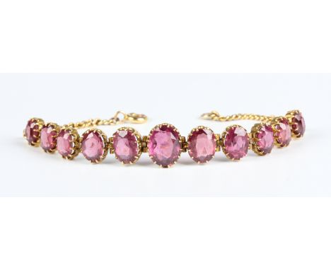 An Edwardian gold and garnet bracelet, circa 1910, claw set with a row of graduated oval cut garnets, on a curblink bracelet 