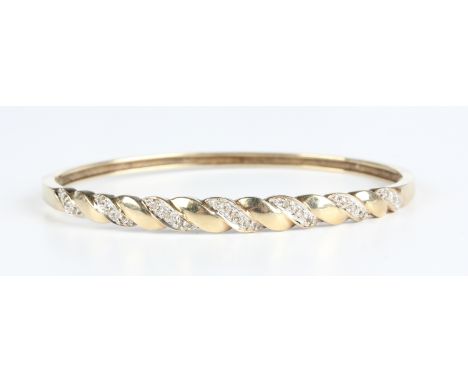 A gold and diamond oval hinged bangle, the front in a ropetwist design, mounted with rows of circular cut diamonds, detailed 
