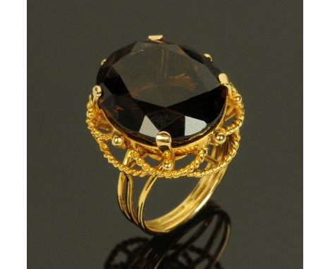 A gold coloured metal ring, set with a faceted amber coloured stone, size M. 