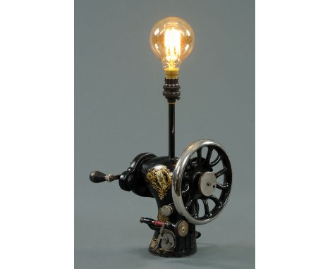 A hand cranked Singer sewing machine, 19th century, converted to a table lamp, with gilt foliate applied decoration on a blac