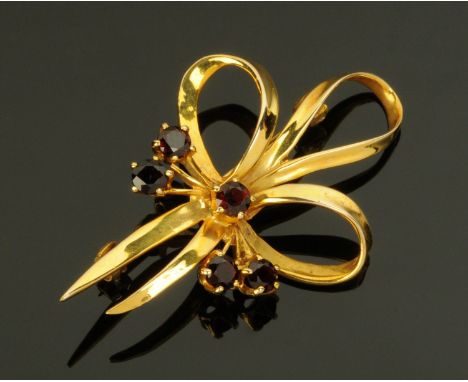 A 9 ct gold bow shaped brooch, set with five garnets.  Gross weight 5.8 grams. 