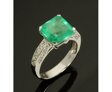 An 18 ct white gold ring, set with an emerald and diamonds to shoulder, total weight +/- 4.45 carats, size M/N. CONDITION REP