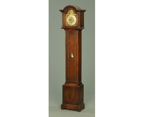 An oak longcase clock, the arched hood with twist columns and glazed door enclosing the silvered brass dial and three-train s