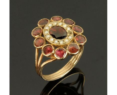 A Victorian rose coloured gold metal ring, set with small seed pearls and garnet coloured stones, size M/N. 