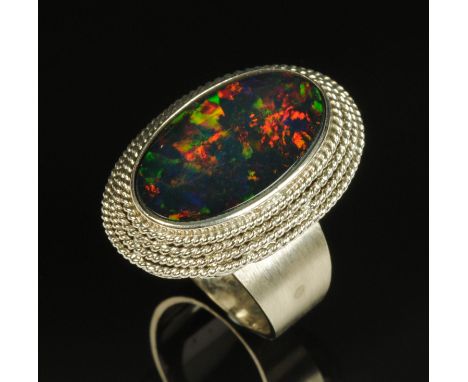 A Chinese white gold coloured metal ring, stamped "18K", the tiered setting with large black opal.  Opal 25 mm x 15 mm, size 