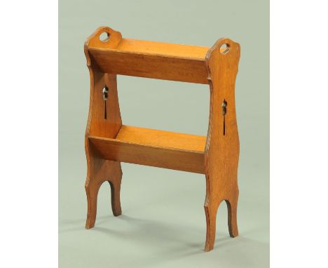 An Arts &amp; Crafts oak floor standing book trough, two tier, with pierced silhouette supports.  Width 53.5 cm, height 76 cm