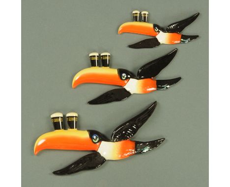 A graduated set of three Carltonware "Guinness" advertising wall plaques, modelled as toucans in flight, each balancing two p