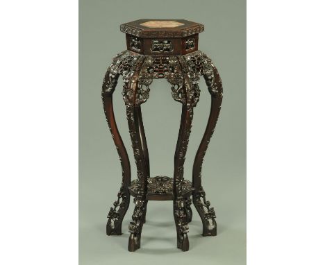 A Chinese hardwood jardiniere stand, with hexagonal top, pierced sides and raised on six legs united by a low circular pierce