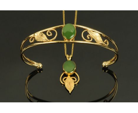A gold coloured metal bangle, set with polished jade centre flanked by scrolling leaves and a matching pendant necklace, each