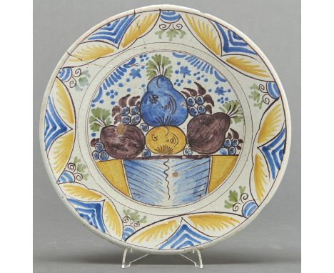 A Dutch polychrome Delftware dish, c1770, painted in cobalt, green, manganese and yellow with fruit in lunette border, the un
