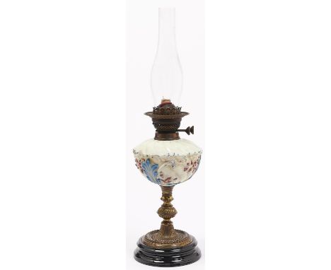 A Victorian brass oil lamp, with enamelled, spirally lobed coloured glass fount, on black glazed earthenware foot, brass burn