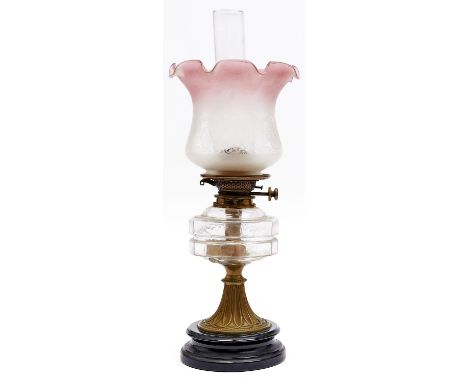 An Edwardian brass oil lamp, c1910, with moulded glass fount, on black glazed earthenware base and an etched glass lampshade,