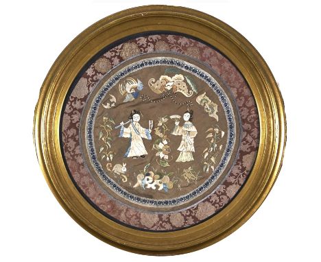 A Chinese embroidered silk roundel, 19th / early 20th c, worked with figures and flowers in a surround of auspicious emblems 