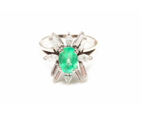 AN 18K WHITE GOLD FACETED EMERALD &amp; DIAMOND RING Oval step cut emerald of vivid green colour  Very good clarity, surround