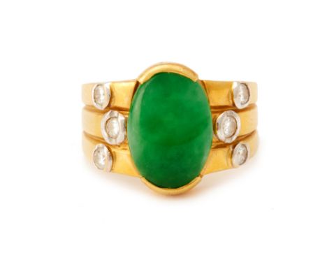 A DIAMOND AND CABOCHON JADE RING
The oval green jade cabochon set between three collet set round brilliant cut diamonds to ea