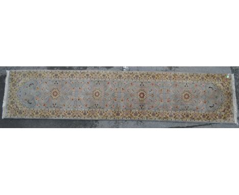 A large 20th century Persian style carpet runner rug. The rug having pale blue central field, with floral scrolled decoration