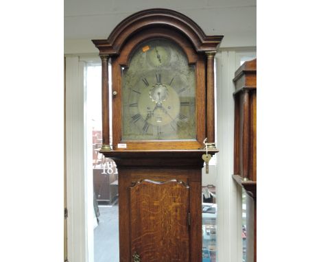 A late 18th/early 19th century oak longcase clock having arch and pillar hood containing brass face and 8 day movement by Pre