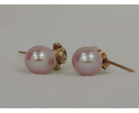 A pair of 9ct gold diamond stud earrings with pink baroque pearl drops