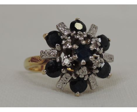 A lady's dress ring having a large sapphire starburst cluster with diamond chips in a raised basket mount on a yellow metal l