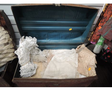 A vintage tin trunk containing a large quantity of vintage net and lace pieces