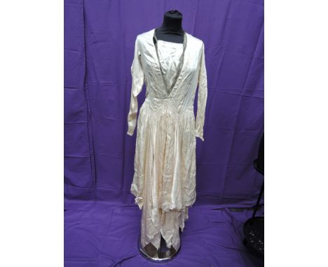 An ivory silk vintage wedding dress having handkerchief hem, smocked detail to waist, leg o mutton sleeves and lace detail to