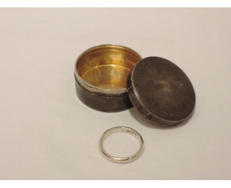 A small HM silver lidded trinket box of circular form having engine turned decoration containing an HM silver wedding band, s