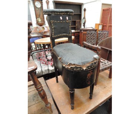 An early Victorian commode chair of cock fighting style, having black leatherette upholstery and ebonized frame