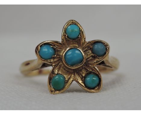 A lady's dress ring having a turquoise set flower head cluster on a yellow metal loop stamped 18ct,  size K