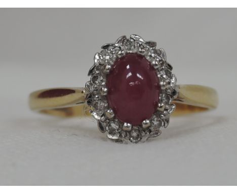 A lady's dress ring having a ruby cabouchon and diamond cluster in an illusionary setting on an 18ct gold loop,  size P/Q