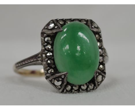 A lady's dress ring having an oval jade style cabouchon in a marciste set mount on a yellow metal loop stamped 9ct, size Osto