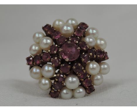 A lady's dress ring of over sized form having cultured pearl and ruby star burst cluster in a basket mount on a yellow metal 